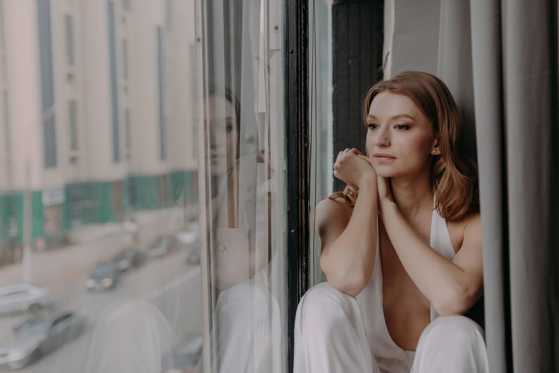 Femme assise près d’une fenêtre dans un moment calme et introspectif